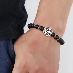 Men's matte black beaded bracelet featuring a silver tree of life charm on wrist