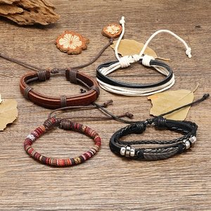Macro detail of bohemian leather bracelets with silver feather charm on wooden background