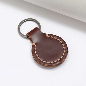 Détail macro du porte-clés en cuir marron foncé avec couture blanche faite à la main