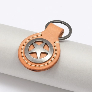 Gros plan du porte-clés en cuir avec étoile, coutures à la main et badge vintage