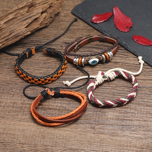 Detailed set of four bohemian woven leather bracelets with evil eye and metal charms