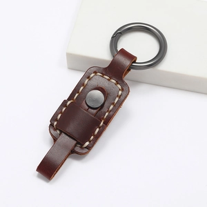Handmade brown leather keychain with vintage stitching and gunmetal ring on white background
