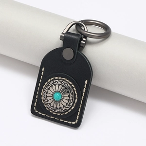 Detail of handmade black leather car keychain with turquoise stud and white stitching