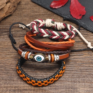 4-piece bohemian woven leather bracelet set with blue evil eye charm on wood surface