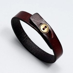 Detail of dark brown leather bracelet with vintage brass button closure texture