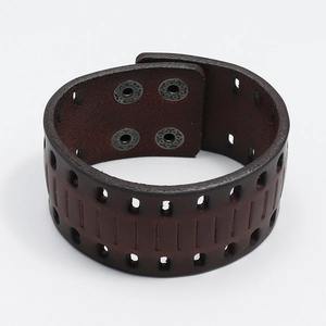 Close-up of vintage brown leather wide wristband featuring cutout details and metal snaps
