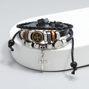 Detail shot of multi-layer leather bracelet with bronze cross pendant and peace sign beads