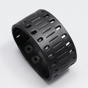 Detail of laser-cut hollow patterns and snap button closures on wide black leather bracelet