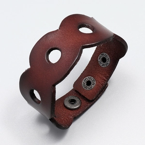 Macro detail of retro wide brown leather bracelet with circular cutouts and snap buttons