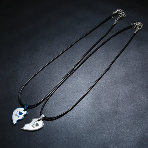 Close-up of split heart pendant necklaces with love you engraving on leather background