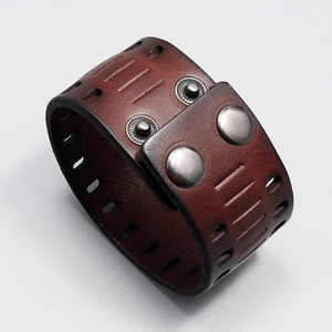 Detail of vintage wide leather bracelet featuring hollow cutouts and metal snap buttons