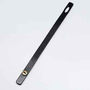 Detail view of black vintage leather bracelet strap with bronze metal button fastener
