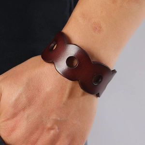 Retro punk style wide brown leather cuff bracelet with hollow circles and wavy edges on wrist