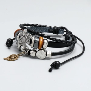 Macro view of multi-layer leather bracelet with cross, maple leaf charms and wooden beads