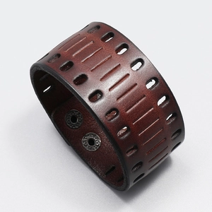 Detail of vintage wide leather bracelet with hollow cutouts and metallic double snap buttons