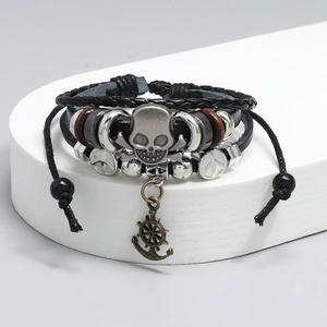 Macro detail of multilayer leather bracelet featuring retro skull and anchor charms
