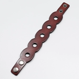 Macro shot of vintage brown leather bracelet featuring hollow circles and metal buttons