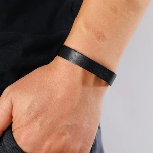Close-up of minimalist black leather bracelet texture and fit on male wrist