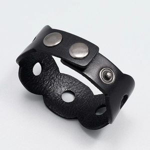 Detail of black leather punk bracelet with hollow holes and silver metal rivets