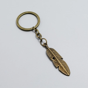 Macro detail of a bronze feather keychain with intricate textures and a vintage finish