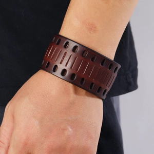 Close-up of retro punk wide leather bracelet with oval cutouts and gradient texture