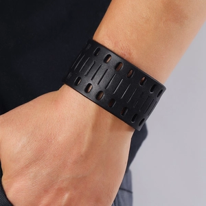 Detail of men's wide black cutout bracelet featuring geometric patterns on a wrist