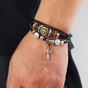 Detail of multi-layer leather bracelet with cross pendant and vintage beaded elements