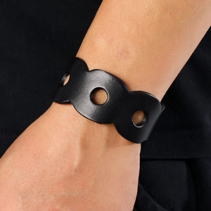 Close-up of black wide leather bracelet featuring three circular cutouts and matte texture