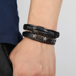 Close-up of men's layered black leather bracelet set featuring vintage silver star accents