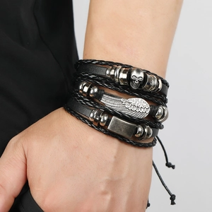 Detail view of layered black leather bracelets with skull and feather metal charms