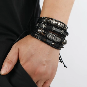 Detailed view of layered leather bracelets featuring feather charms and punk metal studs