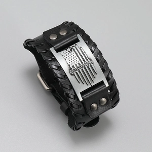 Detail of vintage braided leather bracelet featuring engraved metal plate and punk rivets