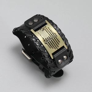 Macro detail of punk leather bracelet with brass plate engraved Reload Freedom and US flag