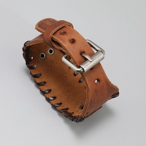 Detail of vintage brown leather bracelet featuring hand-woven edges and silver buckle