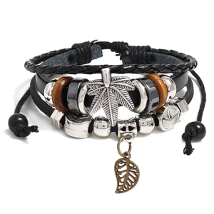 Multilayer punk leather bracelet with beaded cross and cannabis leaf charm on white backdrop