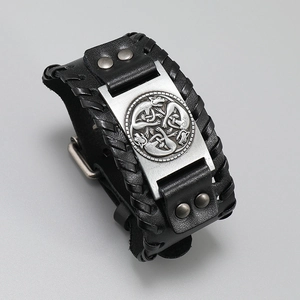 Detailed close-up of a wide leather bracelet with Nordic wolf engraving and woven edges