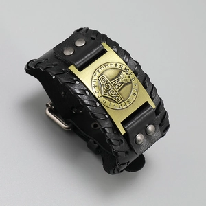 Detailed close-up of a bronze Mjölnir pendant on a wide black braided leather bracelet