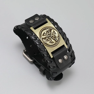 Macro shot of black woven leather bracelet featuring a Celtic wolf bronze metal plate