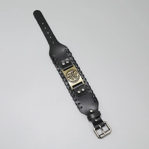 Detail of black leather bracelet with bronze Celtic Knot metal plate and woven edges