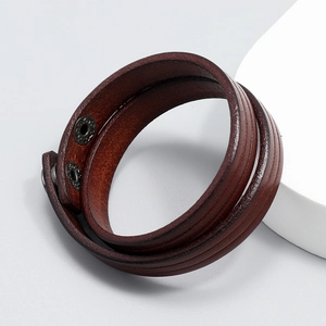 Close-up of double-wrapped reddish brown leather bracelet with vintage metal snap closure