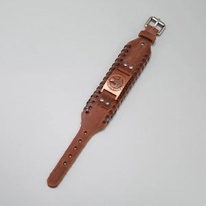 Macro view of vintage brown leather bracelet with bronze Thor's hammer and runes