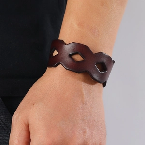 Close-up of a wide dark brown leather bracelet featuring geometric diamond hollow cutouts
