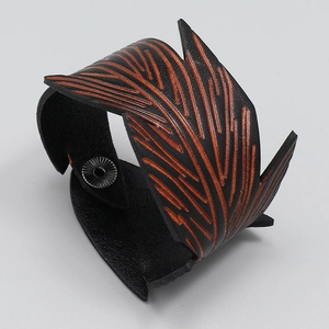 Detail of vintage men's wide leather bracelet with orange leaf vein embossed texture
