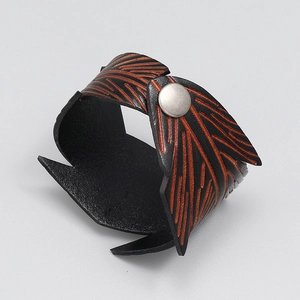 Macro shot of punk style wide leather bracelet with orange leaf veins and silver snap button
