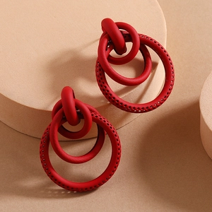 Detail of red geometric triple hoop earrings with perforated texture on warm display