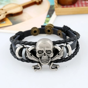 Dettaglio del bracciale in pelle intrecciata con teschio in metallo su sfondo di legno