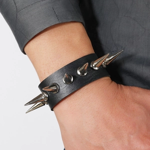 Punk style black leather bracelet with silver metal long spikes worn on a male wrist