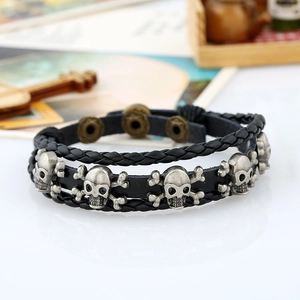 Detail of multi-layer black braided leather bracelet with vintage silver skull charms