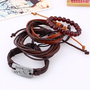 Detail of multi-layer leather bracelets with wooden beads and engraved Love metal charm