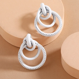Minimalist white multi-layered geometric hoop earrings on a beige display stand